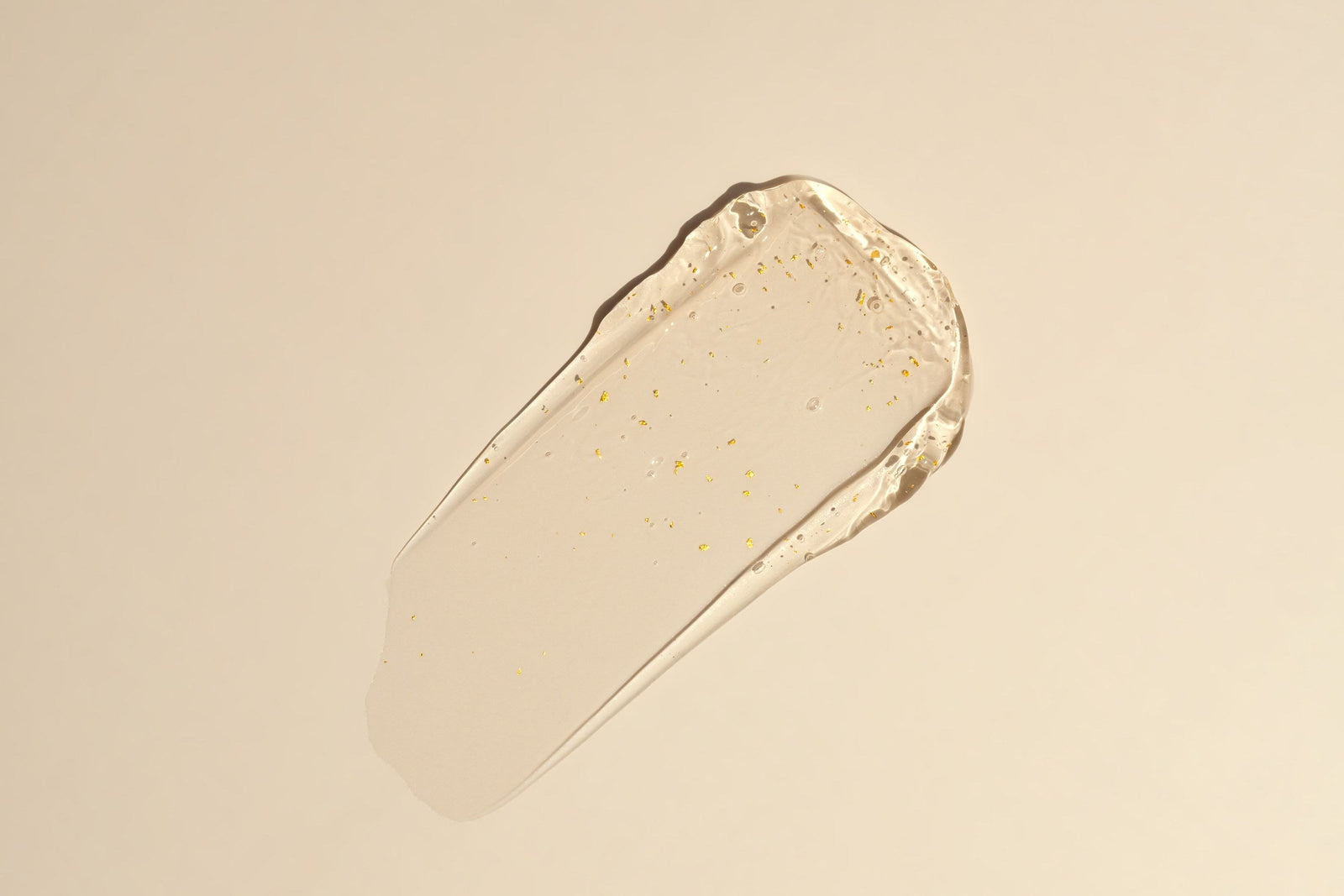 Textura de gel cosmetico dorado sobre fondo beige